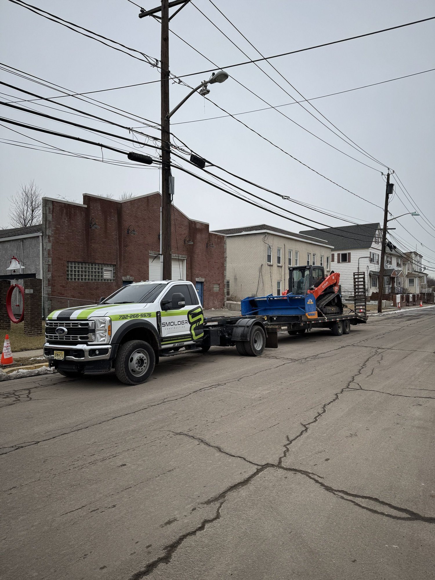 Smolder Construction truck hauling a skid steer and snow pusher box